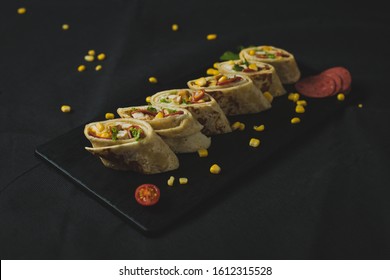 Close up horizontal image (Flat-lay) of vegetable Tortillas / Burritos on black board taken on a textured black background.