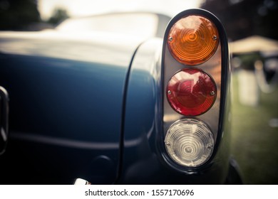 Close up horizontal image of the red tail light of a blue classical vintage car.