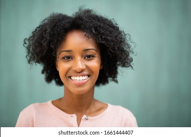 Close up horizontal portrait beautiful young black woman smiling by green background