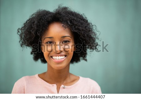 Close up horizontal portrait beautiful young black woman smiling by green background
