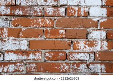 A close up horizontal shot captures the textured detail of a red brick wall covered in peeling, faded white paint with visible mortar lines.