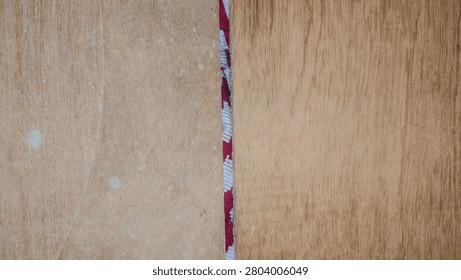 Close up horizontal view of a red and white patterned strip dividing two wooden boards.