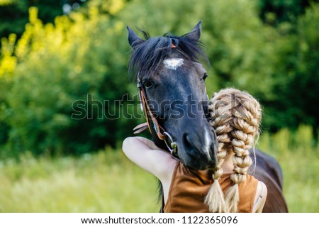 Close up of horse and young blonde woman with two braids hugging. People and animals friendship concept.
