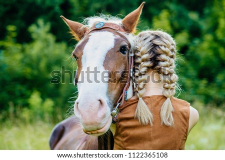 Close up of horse and young blonde woman with two braids hugging. People and animals friendship concept.