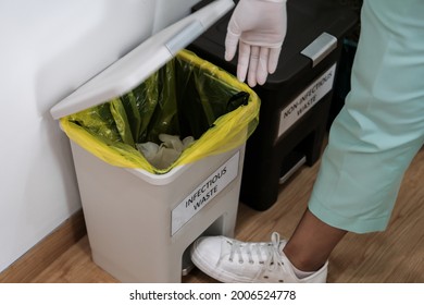 Close Up Of Hospital Worker Discarding Infectious Medical Waste Into Disposal Container Bin. Close Up Of Biohazard Contaminated Clinical Waste