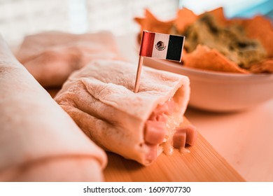 Close up of a hot fresh burrito with the mexican flag and nachos with guacamole cream. The first Thursday in April of every year is the National Burrito day. Teal and orange style. - Powered by Shutterstock