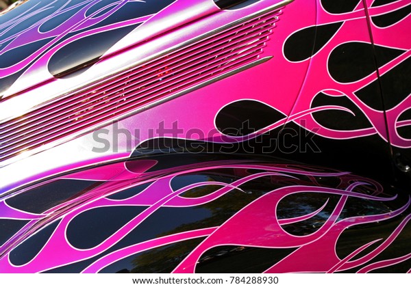 close up of a hot rods hood with pink flames runing\
over the hood and sides