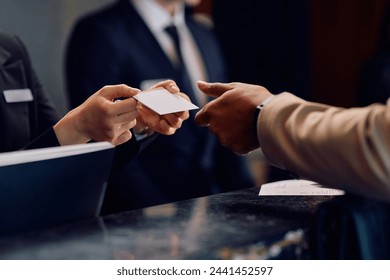 Close up of hotel receptionist giving room cardkey to African American hotel guest. - Powered by Shutterstock