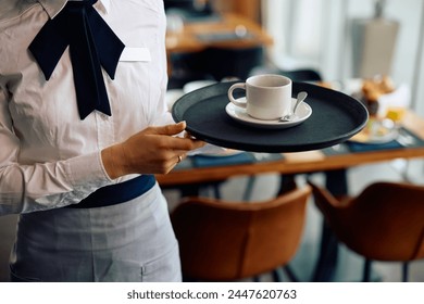 Close up of hotel waitress serving ac up of tea in a restaurant. - Powered by Shutterstock