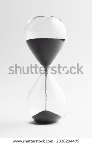 Close up of hourglass with black sand and copy space on white background. Time, timekeeping, shape and colour concept.