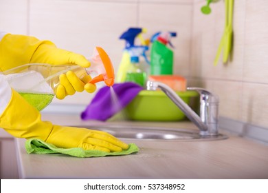 Close Up Of Human Hand In Protective Gloves Holding Cleaning Cloth And Spray Bottle And Wiping Kitchen Counter Top