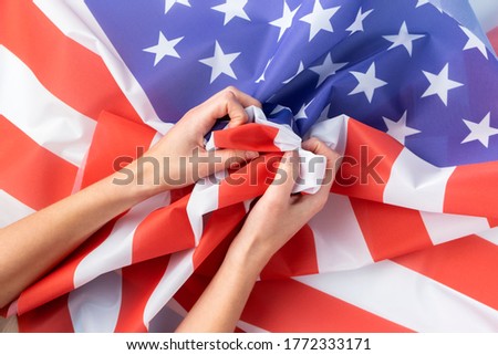 Close up of human hands holding american flag.