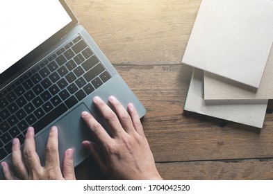 close up human typing or using empty screen laptop on grunge wooden table view from above