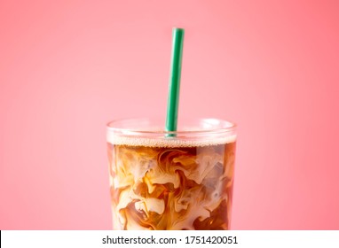 Close up of ice coffee milk on pink background. Cold beverage tasty. Refreshment glass.