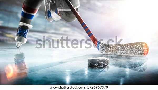 Close up of ice hockey stick on ice rink in\
position to hit hockey\
puck.