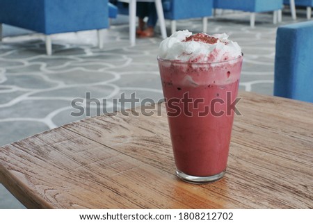 Close up of ice red velvet latte  with whip cream on a wooden table.