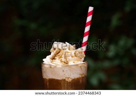 Close up of Iced coffee with cinnamon whip cream and a straw