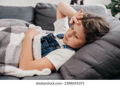 Close up of ill unhealthy little girl child lying alone on couch under blanket in living room at home. Upset small caucasian kid has fever. Concept of health, illness, sickness, common cold, treatment - Powered by Shutterstock