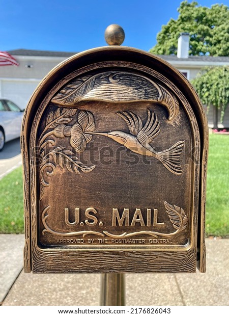 The close up image of an antique, copper finished\
mailbox. It has the words \