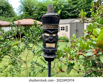 The Close Up Image Of A Backyard Torch In The Shape Of A Tiki Man. These Tiki Torches Add To The Tropical, Resort Appeal Of The Luxurious Backyard. The Torch Is Used At Night For Light And Bugs.