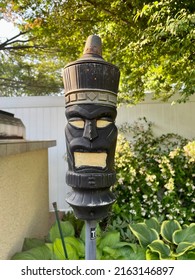 The Close Up Image Of A Backyard Torch In The Shape Of A Tiki Man. These Tiki Torches Add To The Tropical, Resort Appeal Of The Luxurious Backyard. The Torch Is Used At Night For Light And Bugs.