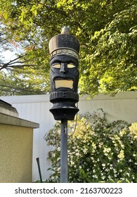 The Close Up Image Of A Backyard Torch In The Shape Of A Tiki Man. These Tiki Torches Add To The Tropical, Resort Appeal Of The Luxurious Backyard. The Torch Is Used At Night For Light And Bugs.