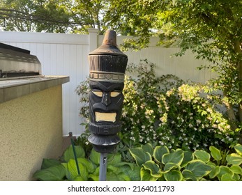 The Close Up Image Of A Backyard Torch In The Shape Of A Tiki Man. These Tiki Torches Add To The Tropical, Resort Appeal Of The Luxurious Backyard. The Torch Is Used At Night For Light And Bugs.