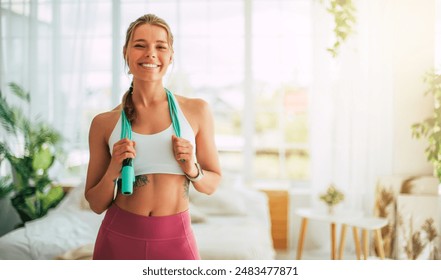 Close up image of beautiful happy excited young sporty slim woman carrying jumping rope on shoulders after home workout and looks on camera. Sport and recreation concept at home. Strong and power - Powered by Shutterstock