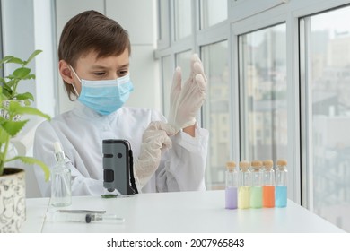 Close up image of boy in mask puting on gloves before chemistry experiments with microscope, curiosity of young scientist, educational concept