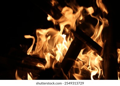 Close up image of burning embers in fire with charred pieces of wood