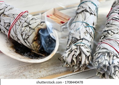 A close up image of a burning white sage smudge stick used for energy clearing and healing. 