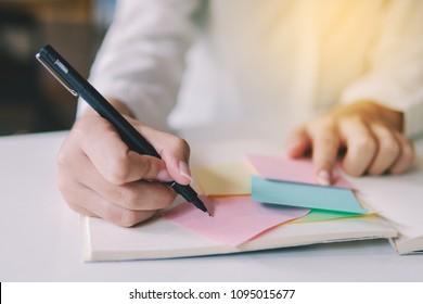 Close Up Image Of Business Hand Writing On An Adhesive Note And Pick Post It At Table In Office, Focus On Hand And Pen.