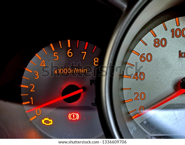 Close up image\
of a car meter dashboard with a light on a engine symbol indicating\
a problem to the car engine.\
