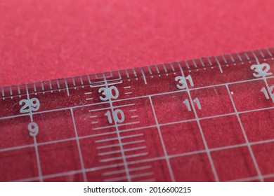 A Close Up Image Of A Clear Metric Ruler With A Light Red Backround