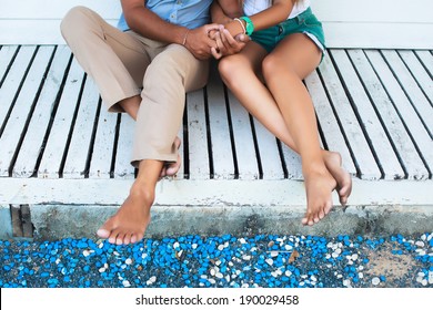 Close up image of couple in love sitting on white wood floor wearing retro outfit. Summer mood.