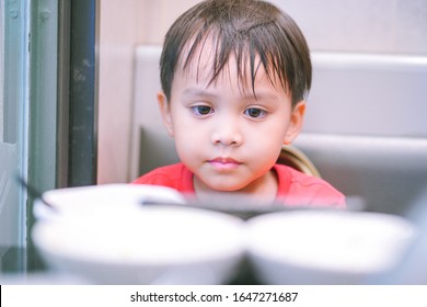 Close Up Image Of Cute Little Child Face Staring At Plate Of Meal On Dinning Table, Anorexia Kid Sitting And Looking At Food On Dinning Table