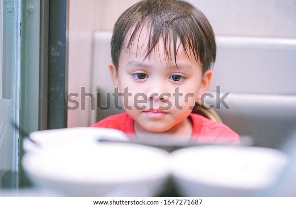 食卓に食事の皿を見つめ 拒食症の子どもが食卓に座って食べ物を眺めている可愛い小さな子どもの顔の接写 の写真素材 今すぐ編集