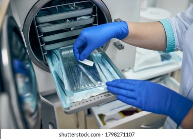 Close up image of dentist assistant hands get out sterilizing medical instruments from autoclave - Shutterstock ID 1798271107