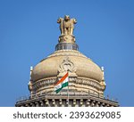 Close up image of dome of largest legislative building in India - Vidhan Soudha , Bangalore with nice blue sky background. Translation of text mentioned is Government work is God