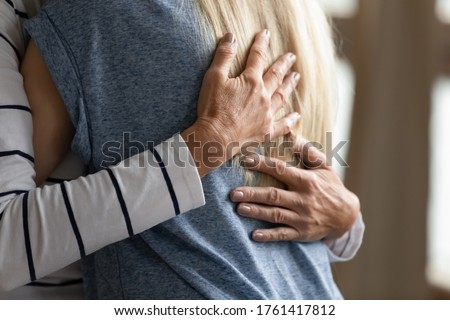 Close up image elderly woman hugs younger relative girl. Grown up adult daughter or granddaughter enjoy moment cuddle to old mom or aged granny. Family bond, together in trouble and happiness concept