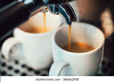 Close up image of espresso pouring into white cups