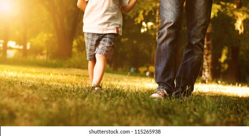 Close up image of father and son legs walk across the lawn in the park - Powered by Shutterstock