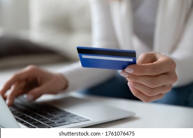 Close up image female sit at table using laptop hold credit card makes payment. E-commerce, e-bank modern tech usage, pay online, safety secure money spend distant purchase from home or office concept