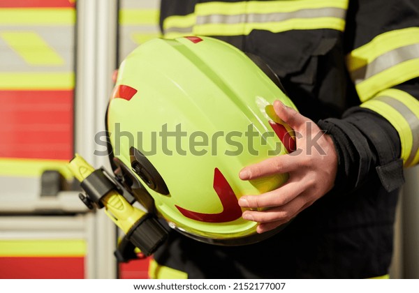 Close up image of a firefighter\'s helmet.\
Firefighter holding a yellow\
helmet