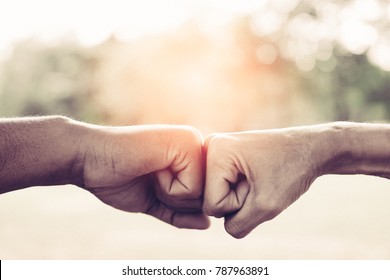 A close up image of a fist bump in vintage tone. Hands of young people show strength teamwork in the nature, team concept.