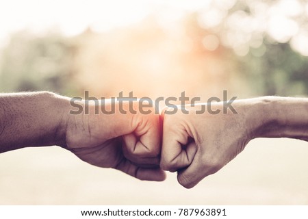 A close up image of a fist bump in vintage tone. Hands of young people show strength teamwork in the nature, team concept.