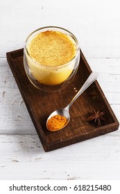 Close up image of golden latte in a wooden box over white wooden table
