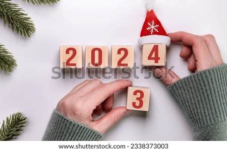 Close up image of hand flipping wood block from 2023 to 2024. Merry Christmas and Happy New Year, white background. 2024 new year idea concept.