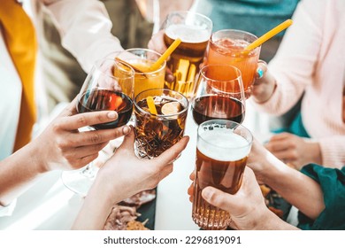 Close up image of hands holding cocktail glasses at bar restaurant - Young people having fun hanging out on weekend day - Food and beverage concept with guys and girls drinking alcohol together 