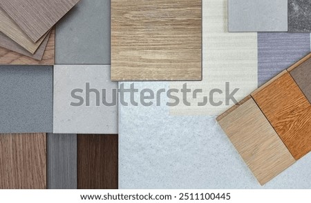 close up image of interior material samples board contains ash vinyl flooring tile, stone ceramic tiles, interior fabric wallpapers, wooden laminated flooring. mood board in close up view.